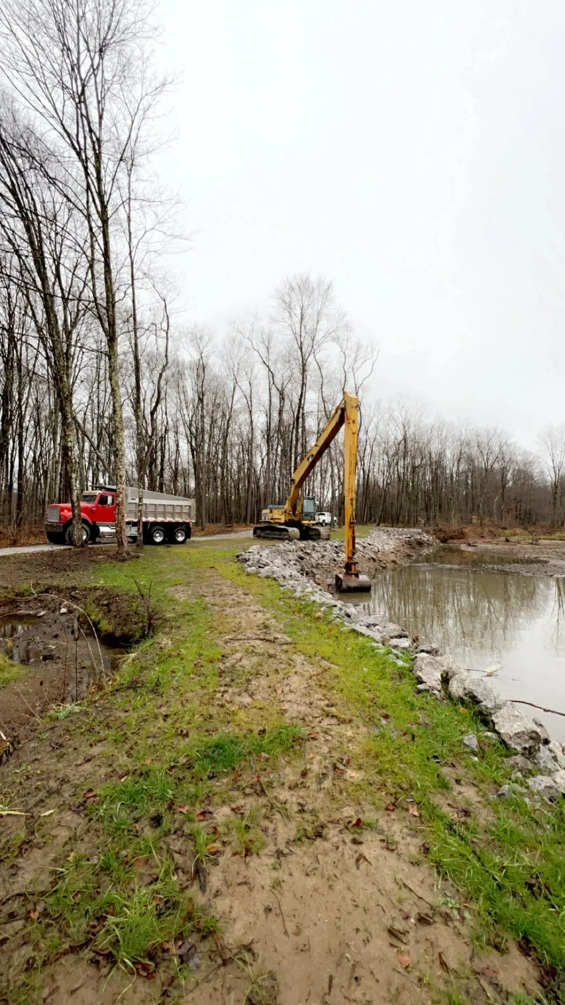 Long-arm excavator and dump truck working a pond build site by Poole Dirt Work