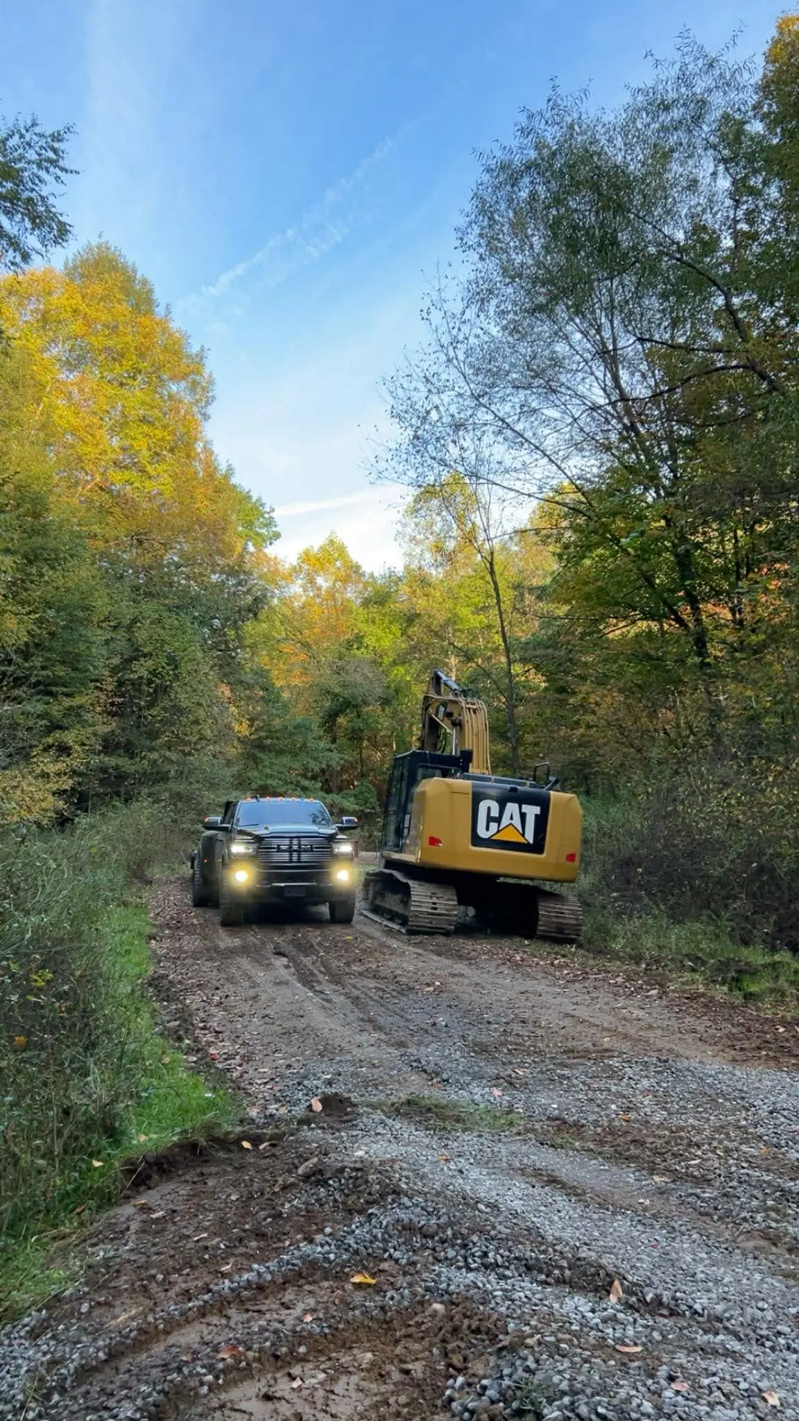 CAT excavator and pickup truck on a forest access road by Poole Dirt Work