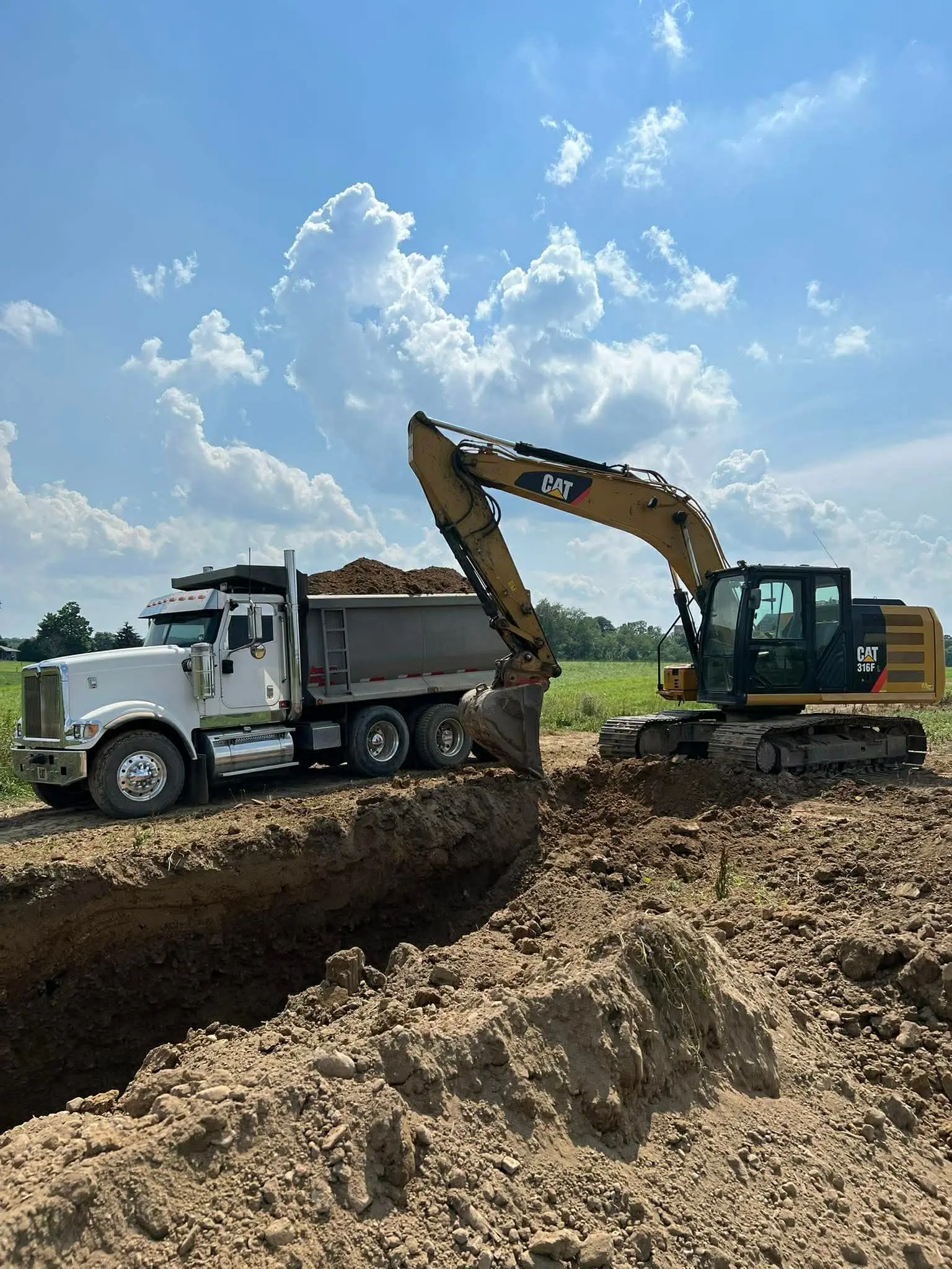 CAT excavator loading a dump truck on an excavation site by Poole Dirt Work